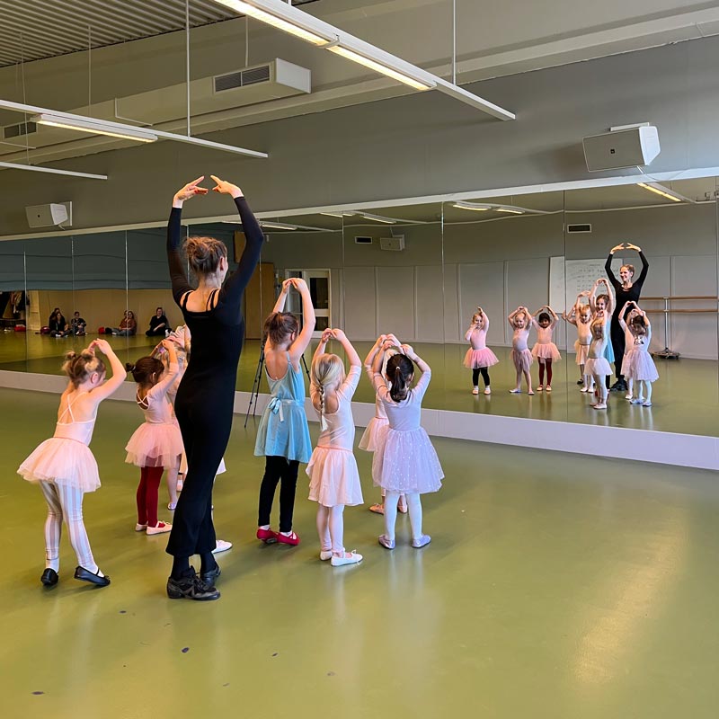 Flera små barn dansar balett i vända mot spegeln.
