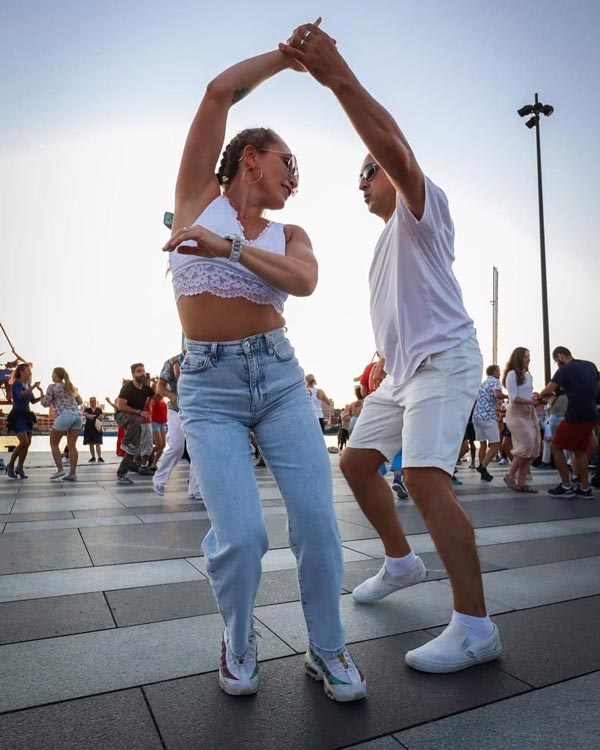 En man och en kvinna i vita kläder dansar salsa ihop.